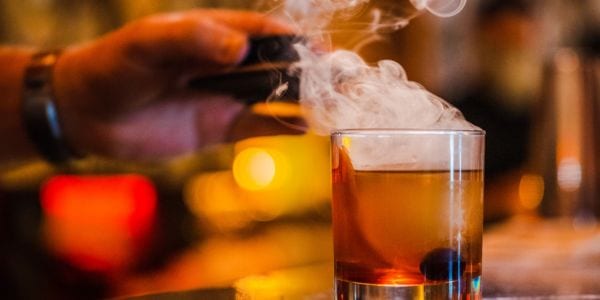 Smoke drifting over a rocks glass at the bar