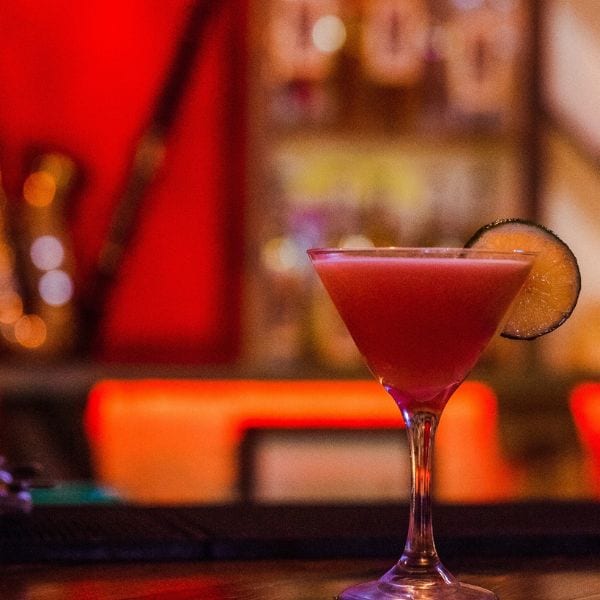 A pink martini with a lime wheel on the bar